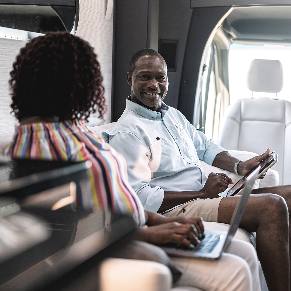 A man and woman sitting on the couch working on their computers in Atlas