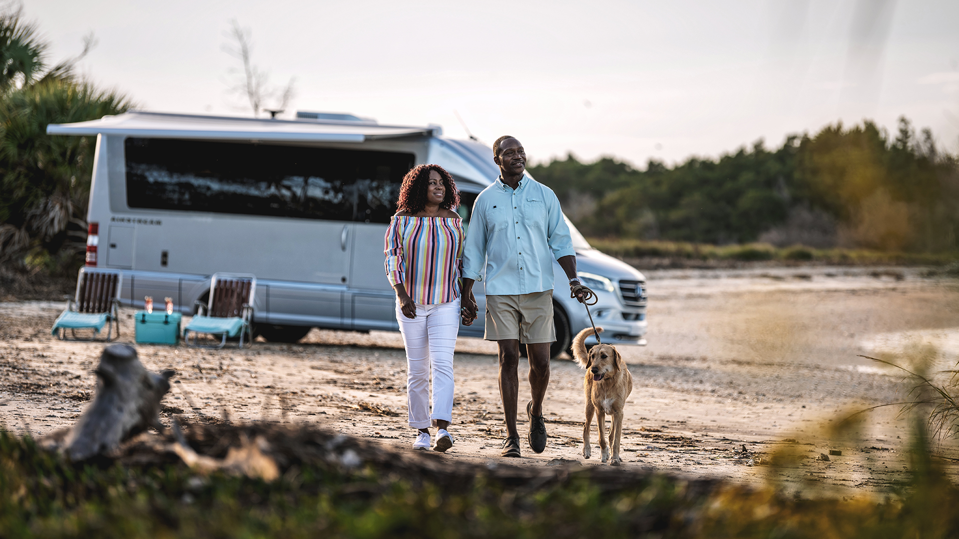 A couple and their dog walking on the beach by their Atlas Mercedes Benz Van