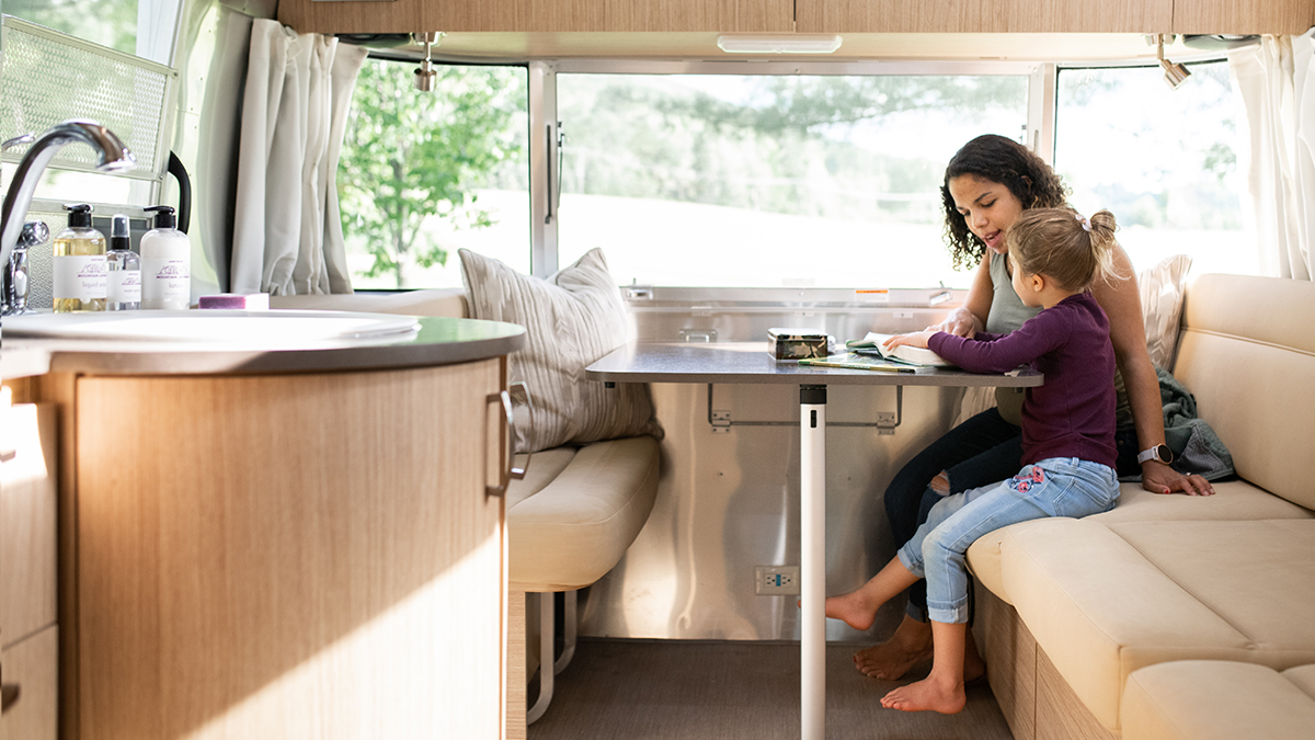 A mother teaching a daughter at the table in their Airstream