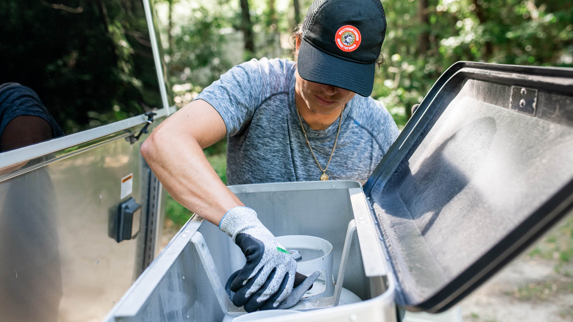 A man dewinterizing his Airstream travel trailer and checking his propane tank.