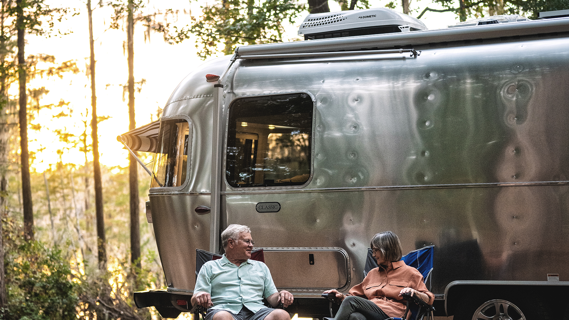 A man and woman sitting beside their Airstream