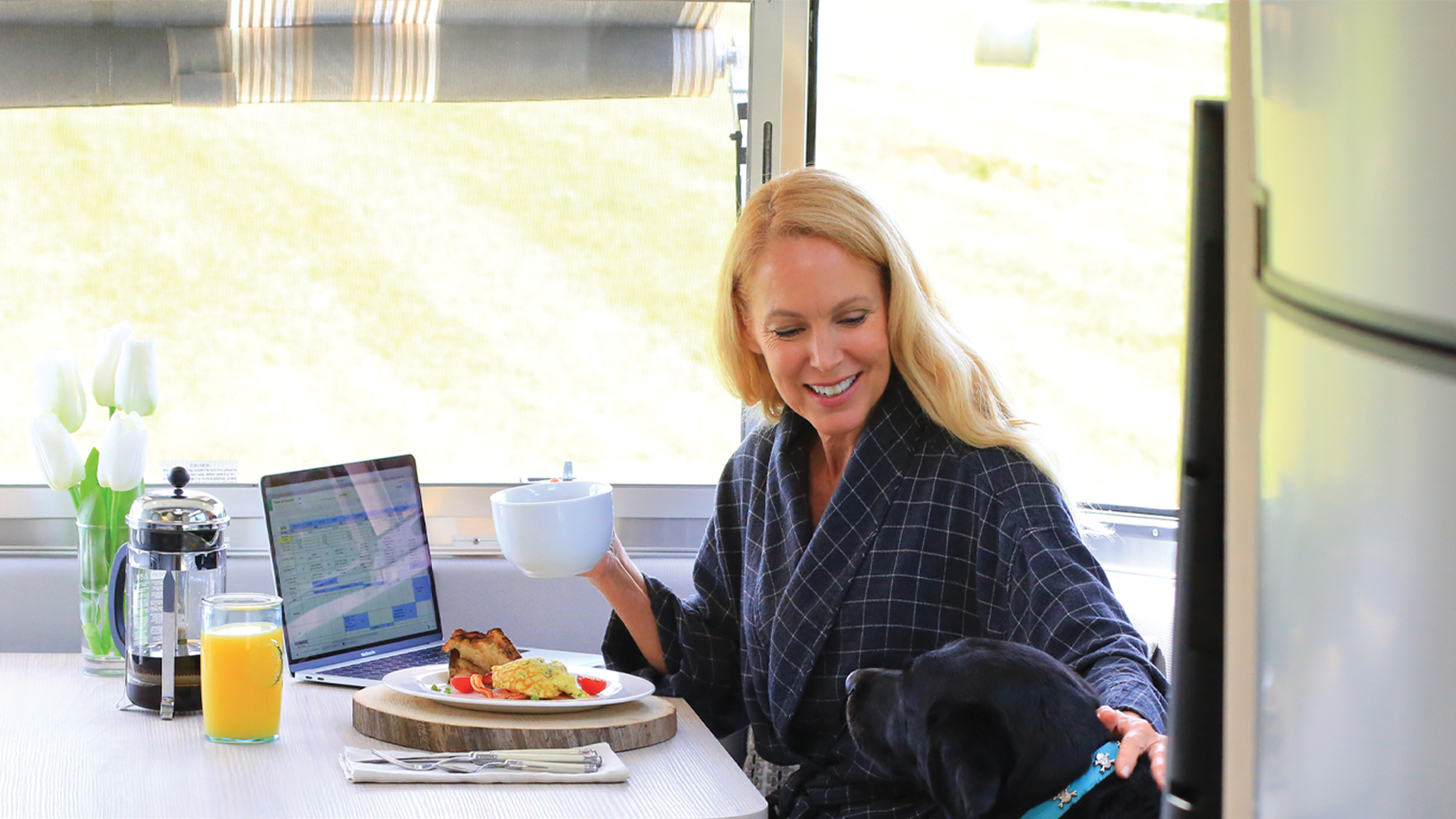 Female Airstreamer sitting in the Galley of her trailer with her dog