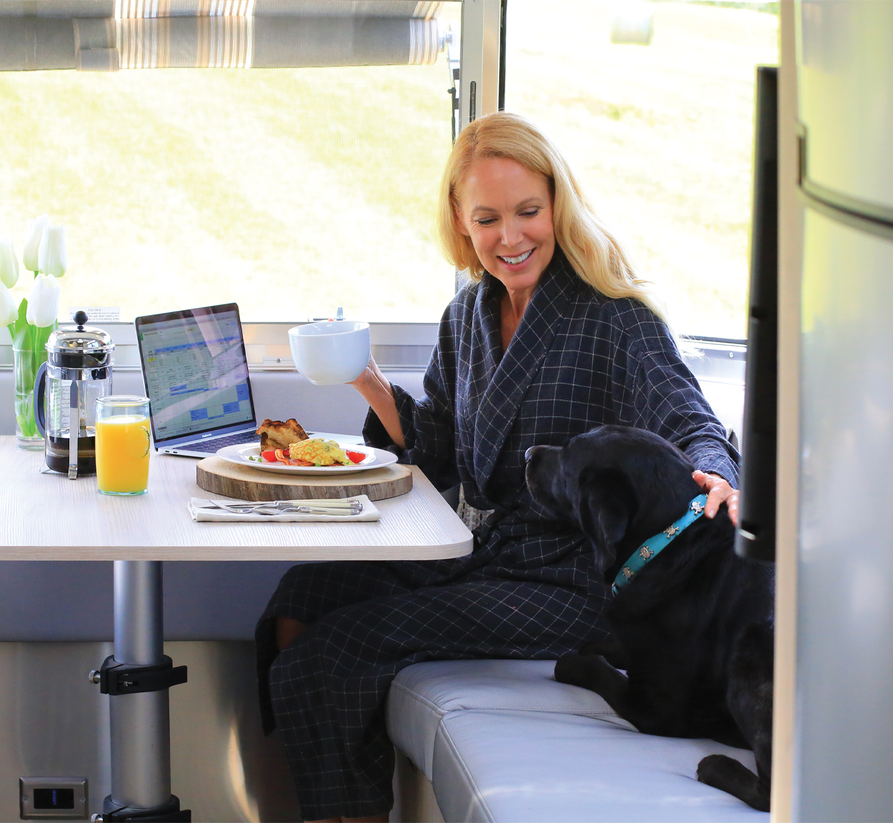 Female Airstreamer sitting in the Galley of her trailer with her dog