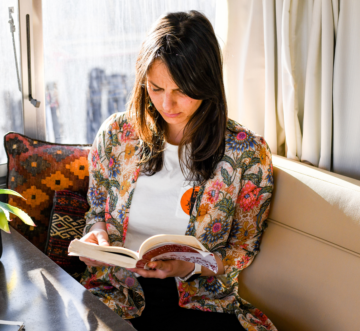 Danielle sitting in the galley of an Airstream Travel Trailer reading a book