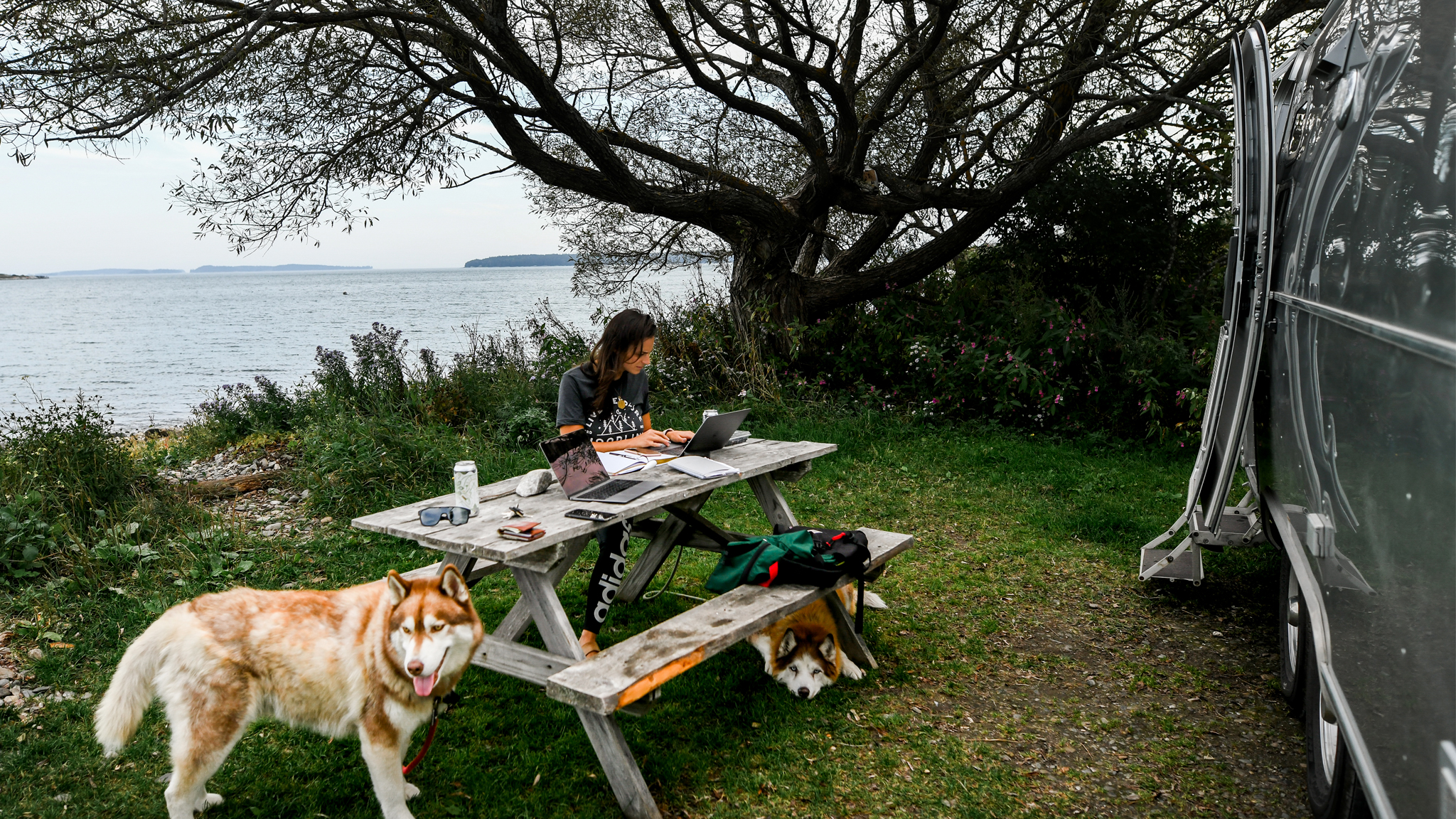 Danielle working at a picnic table outside of her Airstream Travel Trailer