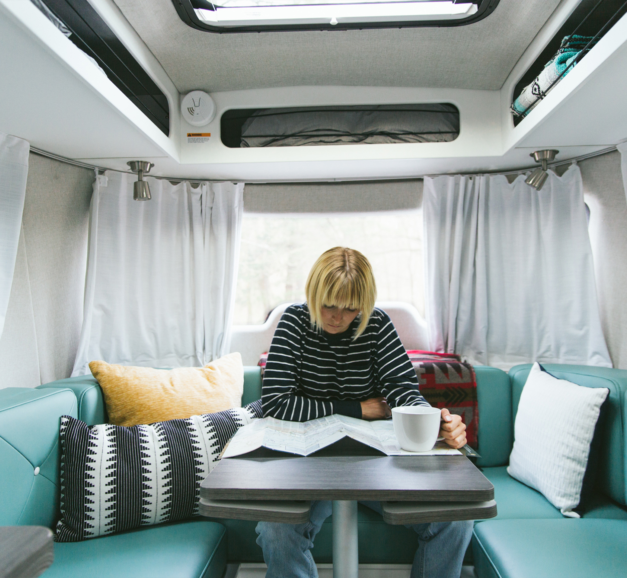 Laura Austin sitting in the galley of her Airstream travel trailer reading a map