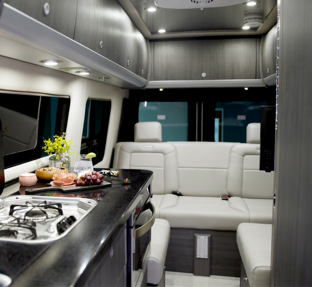 Inside an Airstream Touring Coach Class B Motorhome with lux white interior and a platter of grapes sitting on the kitchen counter.