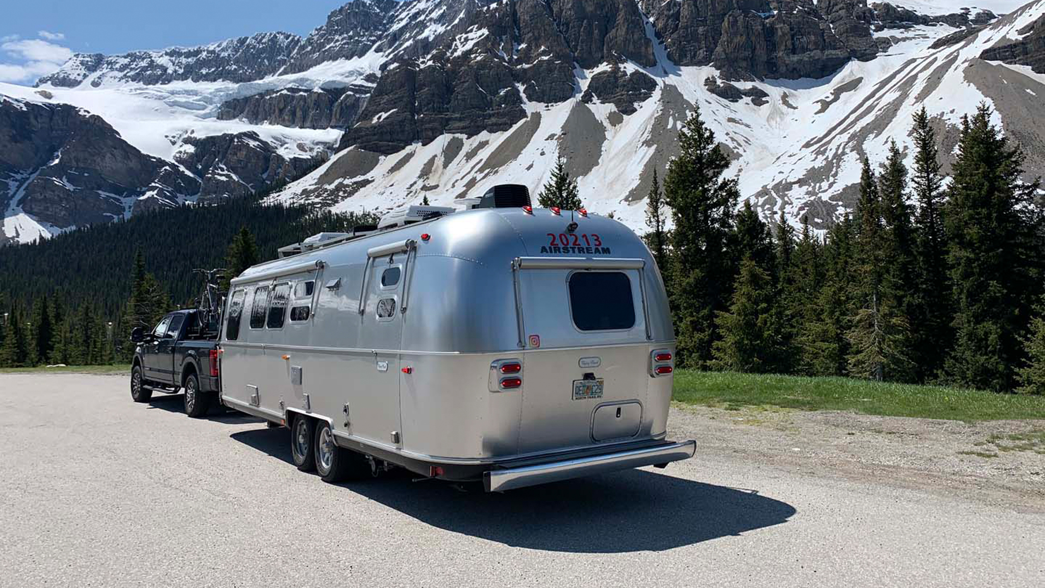 Airstream camper being towed by a truck through snowy mountains.