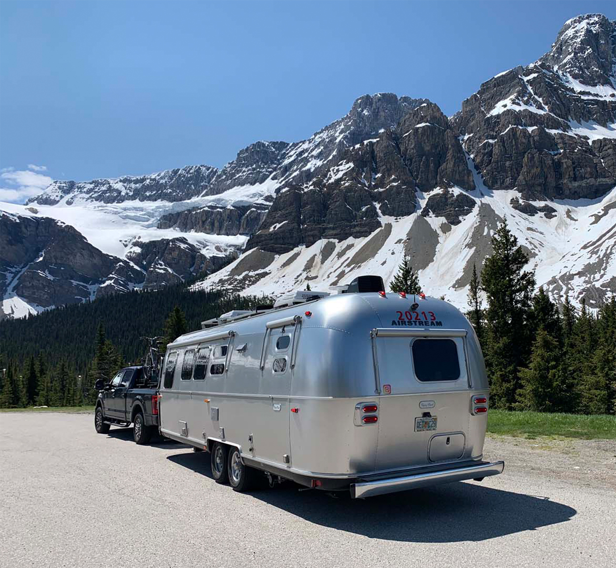 Airstream camper being towed by a truck through snowy mountains.