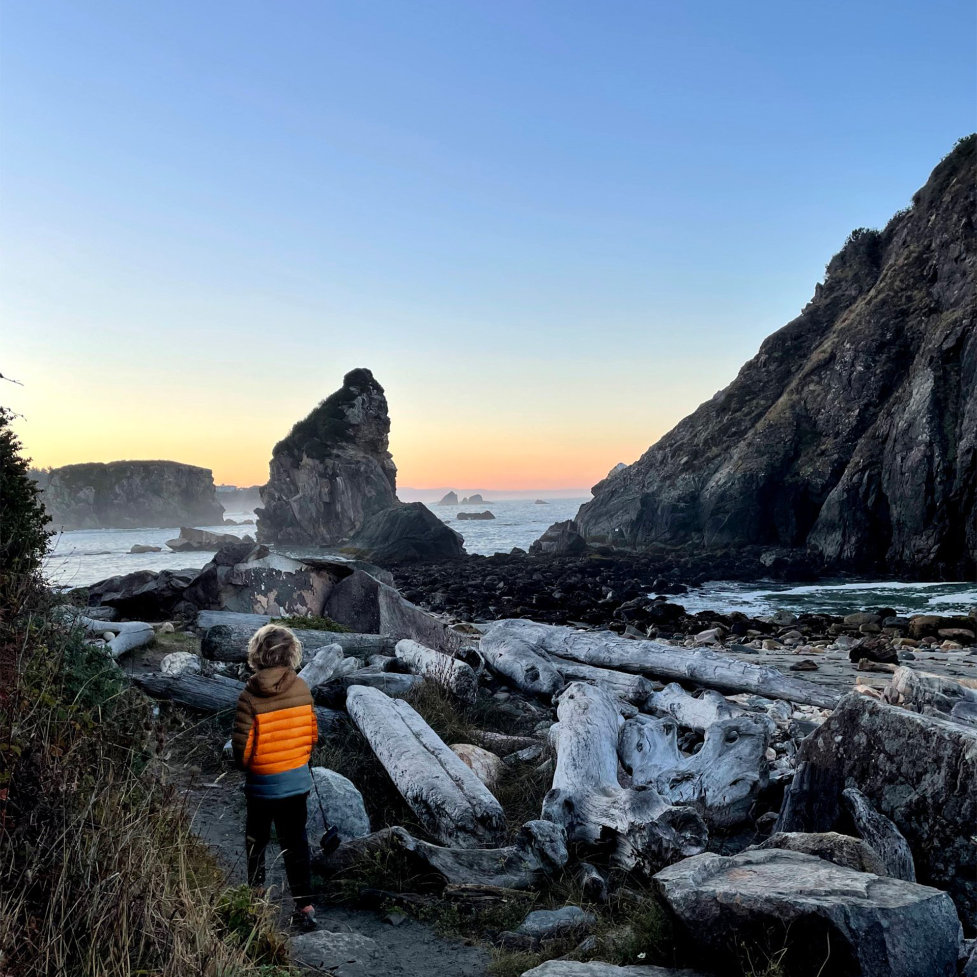A boy walking on a path in between rocks that are in the water.