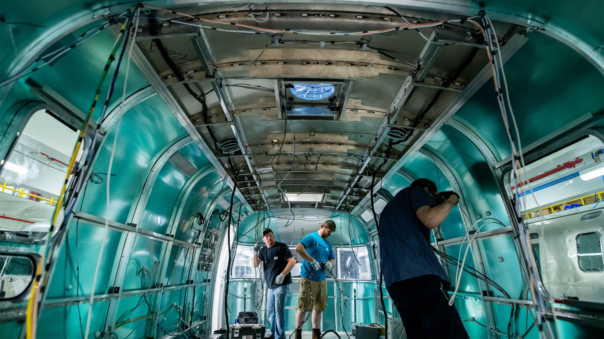 A team at Airstream working on the inside of an Airstream travel trailer installing wires.