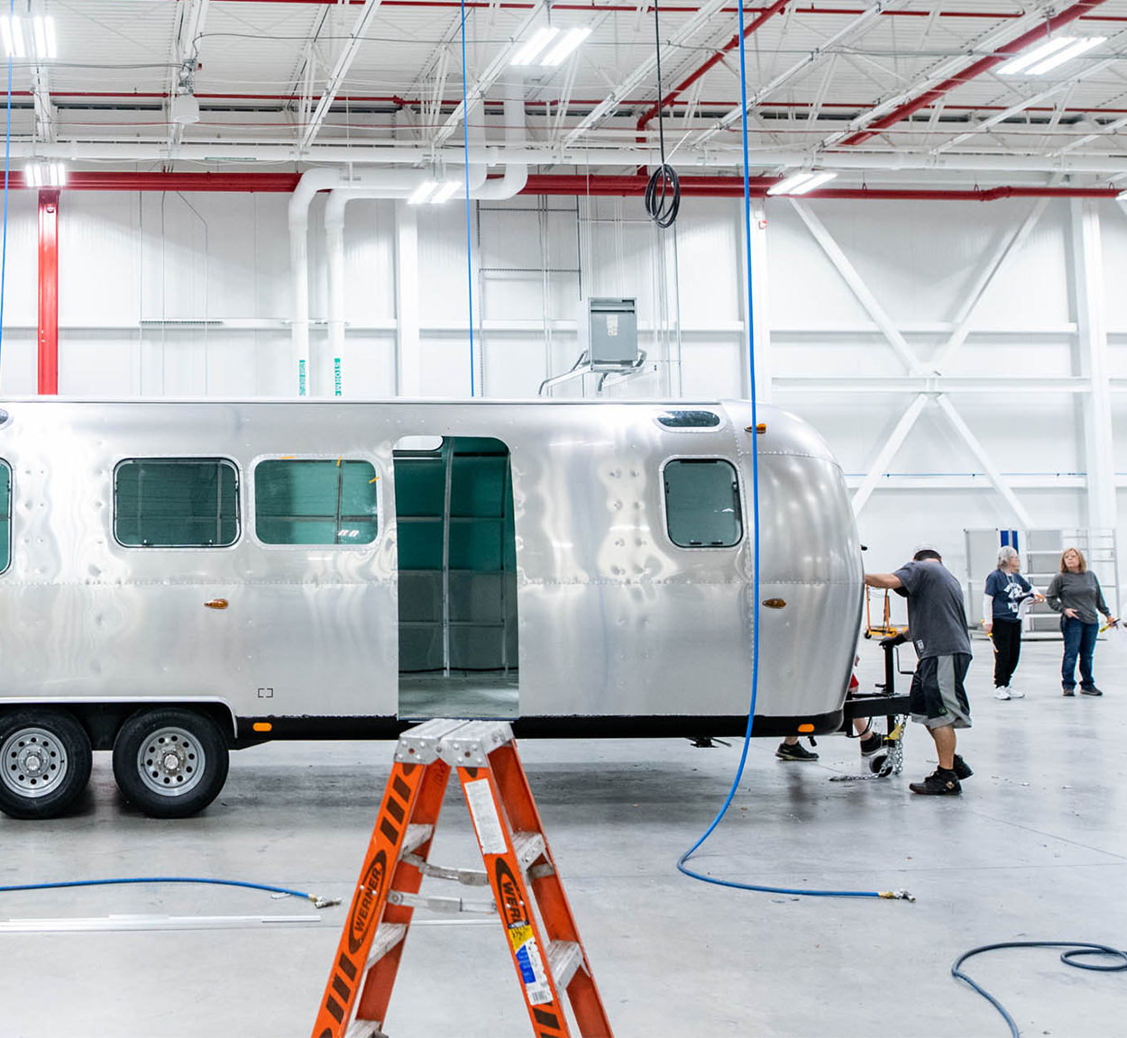 Airstream employees working on the shell of an Airstream Globetrotter travel trailer.