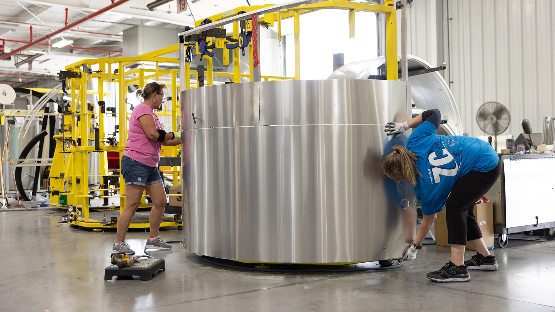Two Airstream employees building the shell of an Airstream Basecamp travel trailer
