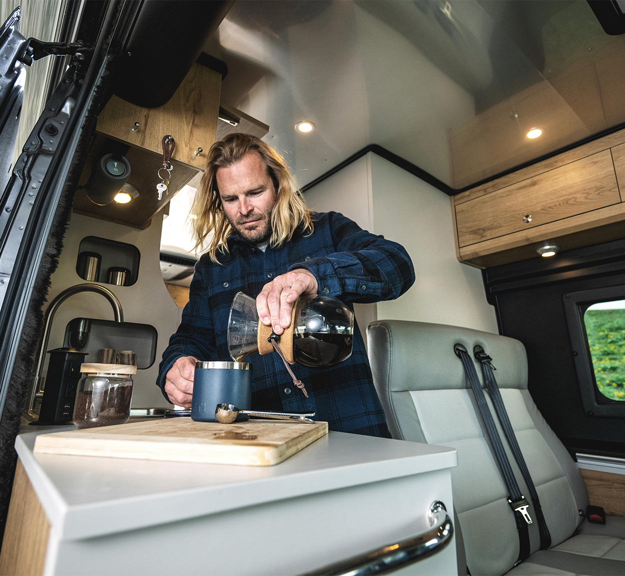 A man making coffee in the galley of his Airstream Rangeline Class B.