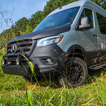 The front of the Airstream 19X Touring Coach going off-road on a grass path.