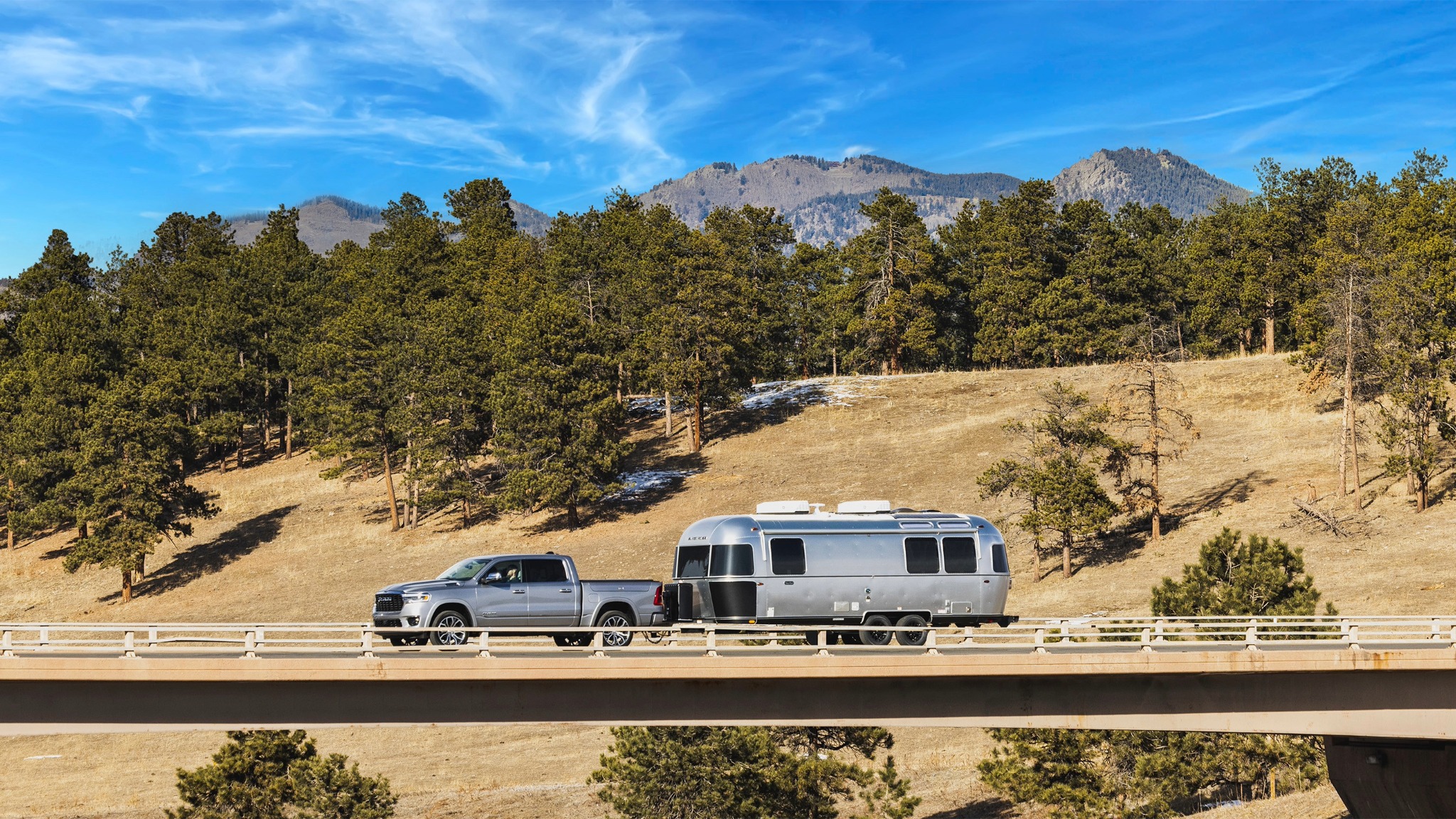 Image of Airstream Midnight Flamingo Travel Trailer being towed in front of mountains