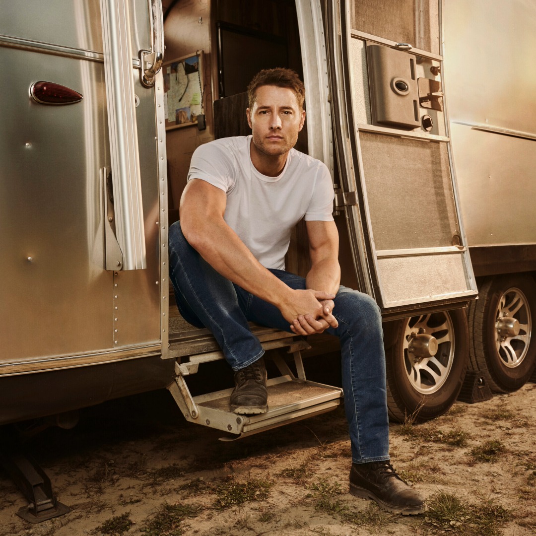 Justin Hartley sitting on the steps of Airstream travel trailer that is featured in the show 'Tracker'