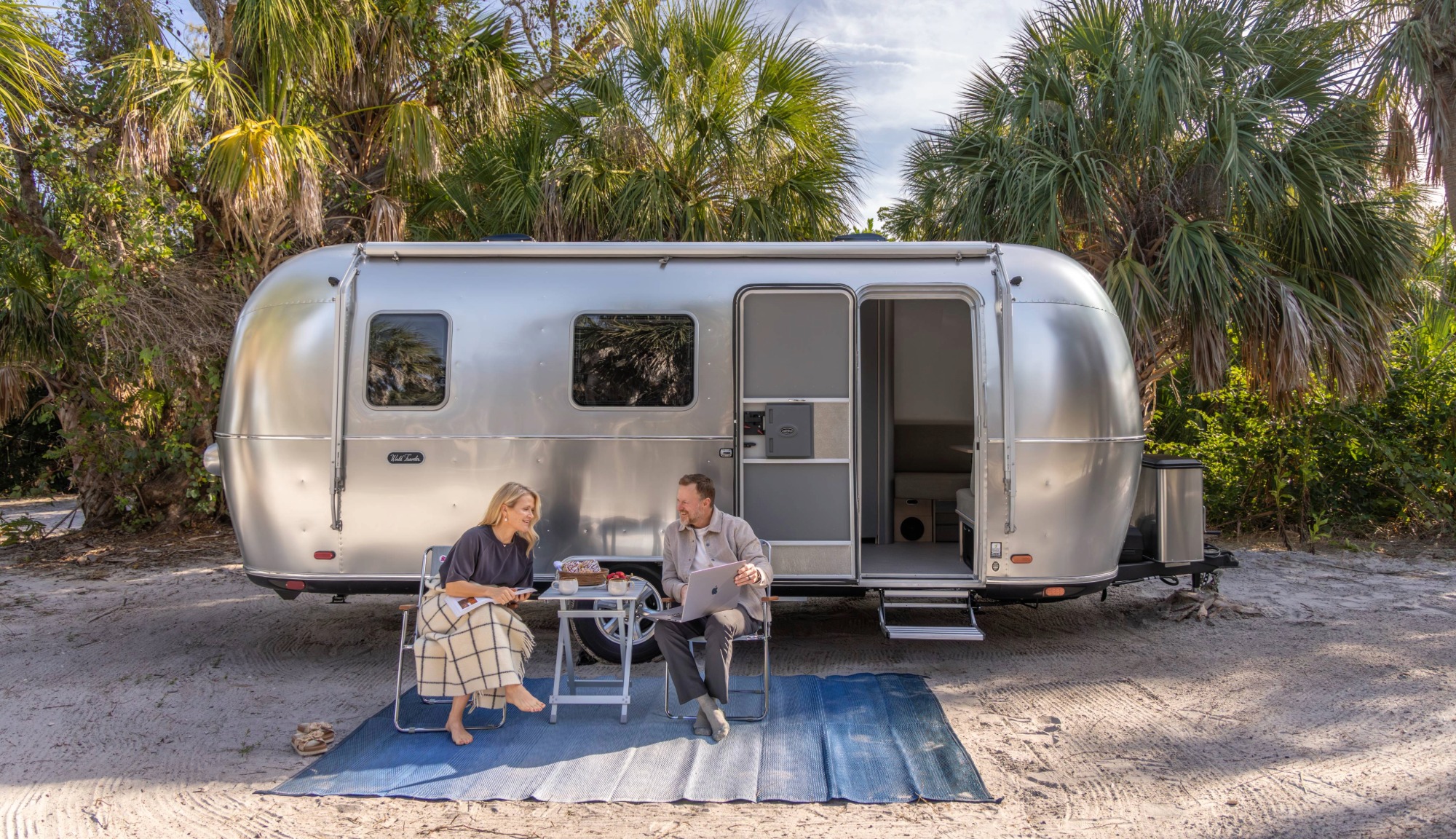 Marc and Tricia, Keep Your Daydream, relaxing on chairs outside the Airstream World Traveler Travel Trailer