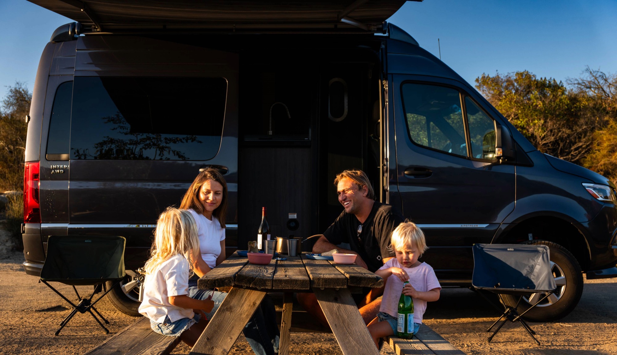 Damien Fahrenfort and his family eating on a picnic table outside an Interstate 19GT Class B Touring Coach
