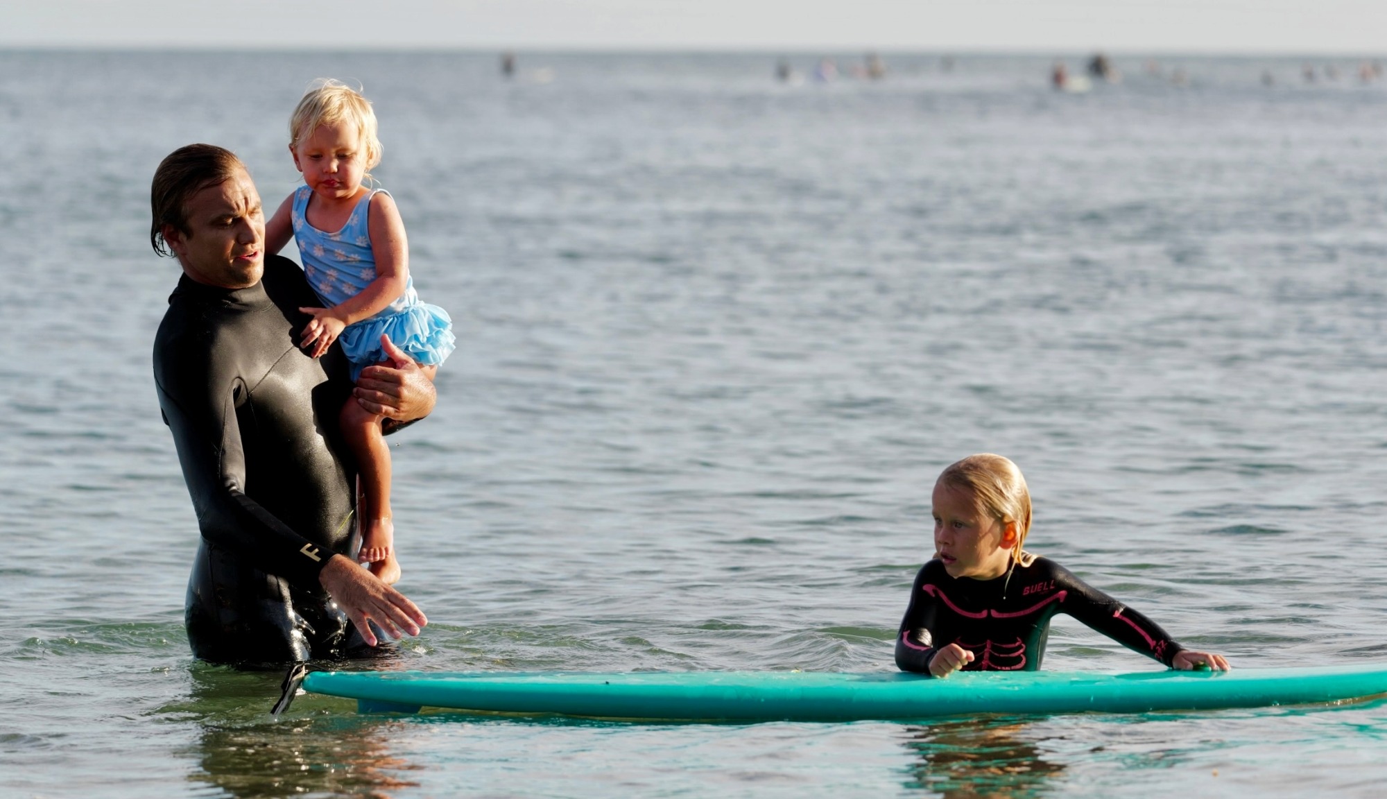 Damien Fahrenfort and daughters in the ocean with a surfboard