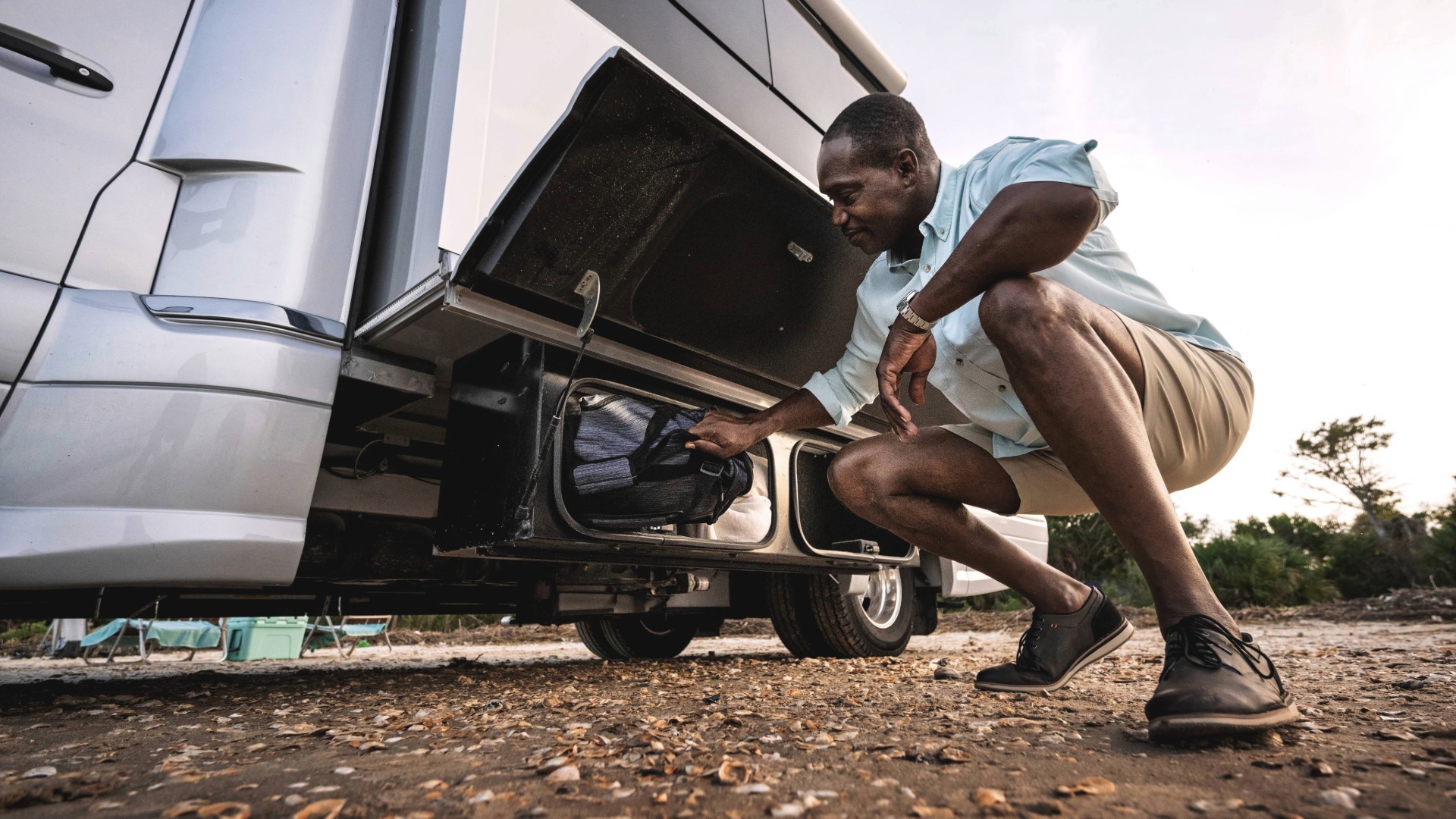 Man loading bags into exterior storage components in the Atlas Class B Camper Van
