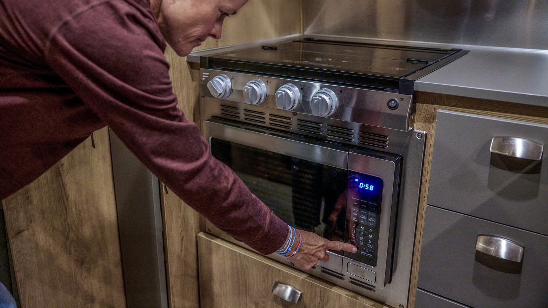 Lady starting the Trade Wind Travel Trailer Microwave using strong boondocking power