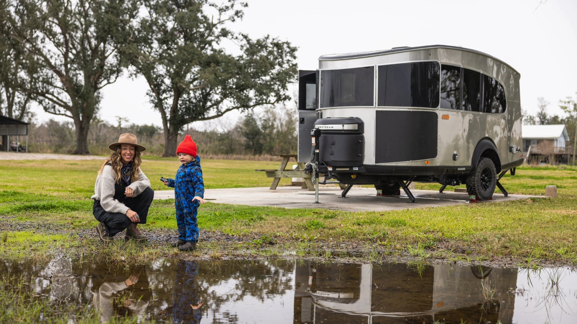 Woman and her son playing in a pond in front of a Basecamp Xe boondocking outside