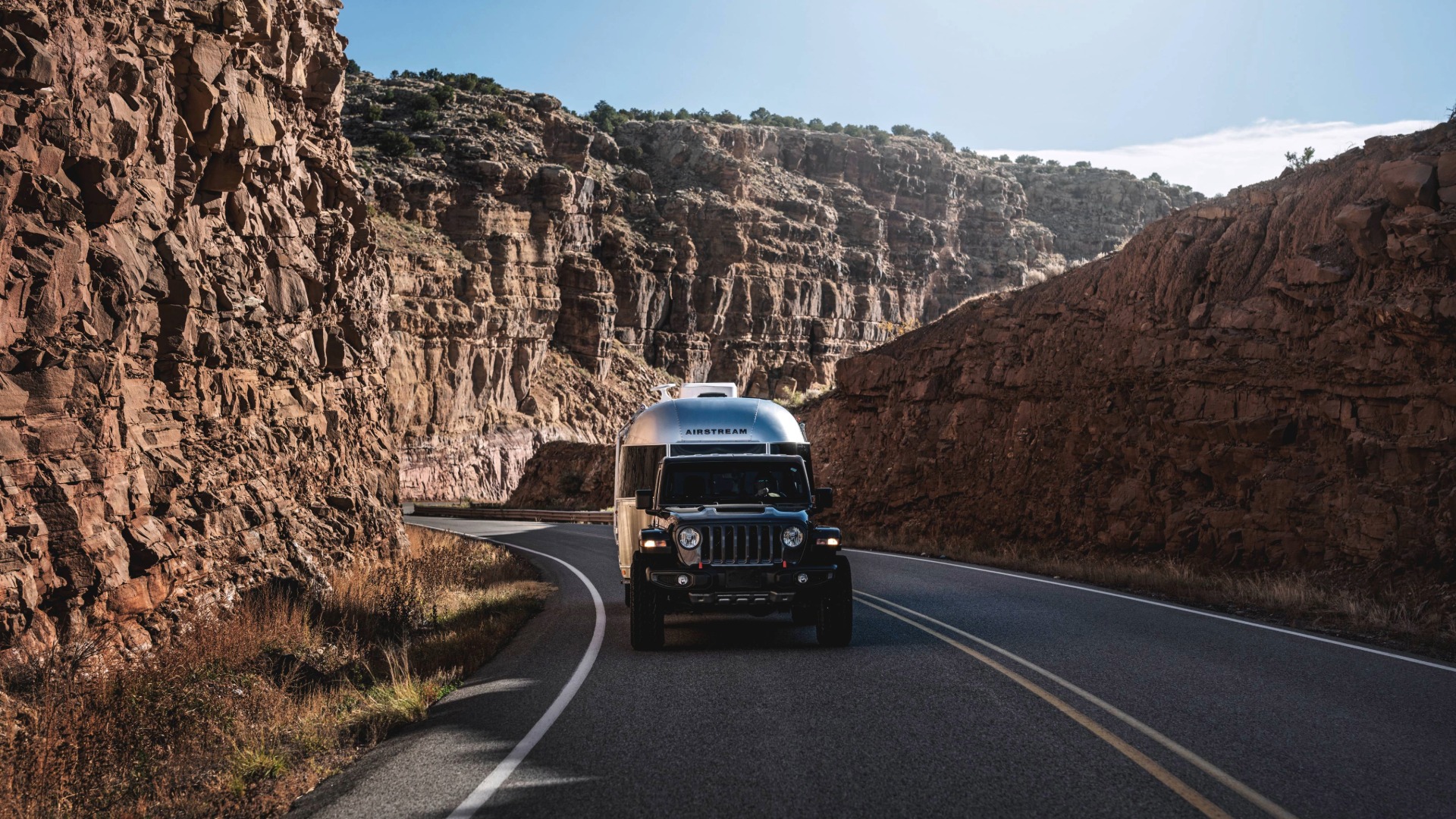 Jeep Wrangler towing Airstream Caravel Travel Trailer in the mountains