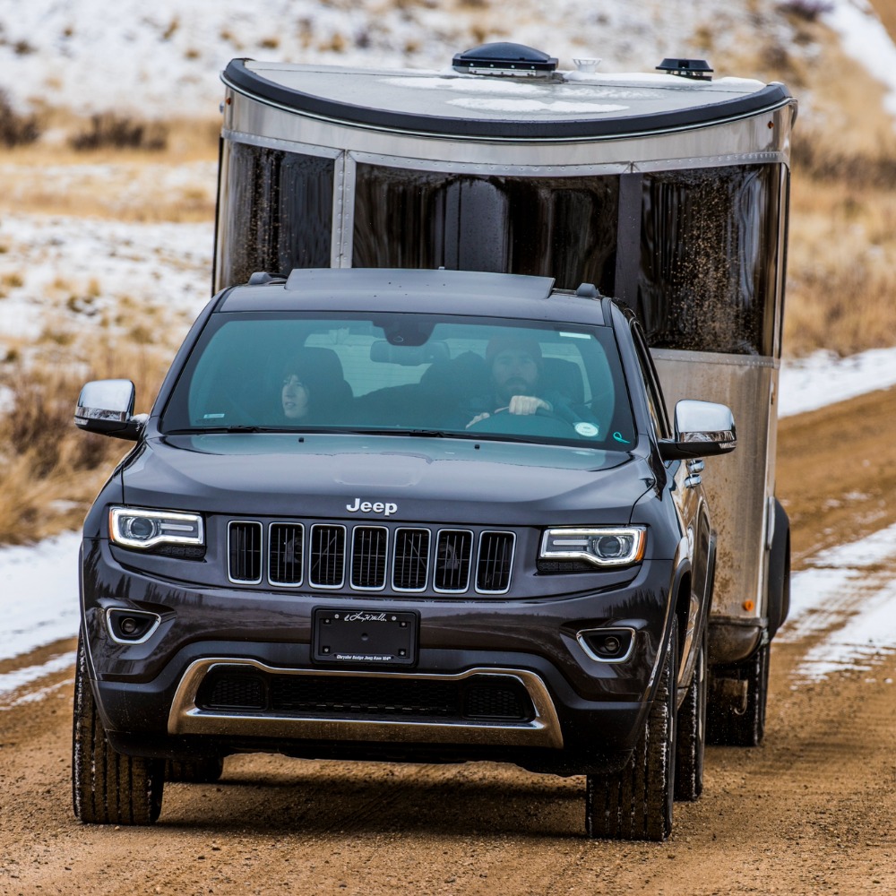 Airstream Basecamp Travel Trailer being towed behind a blue Jeep Grand Cherokee