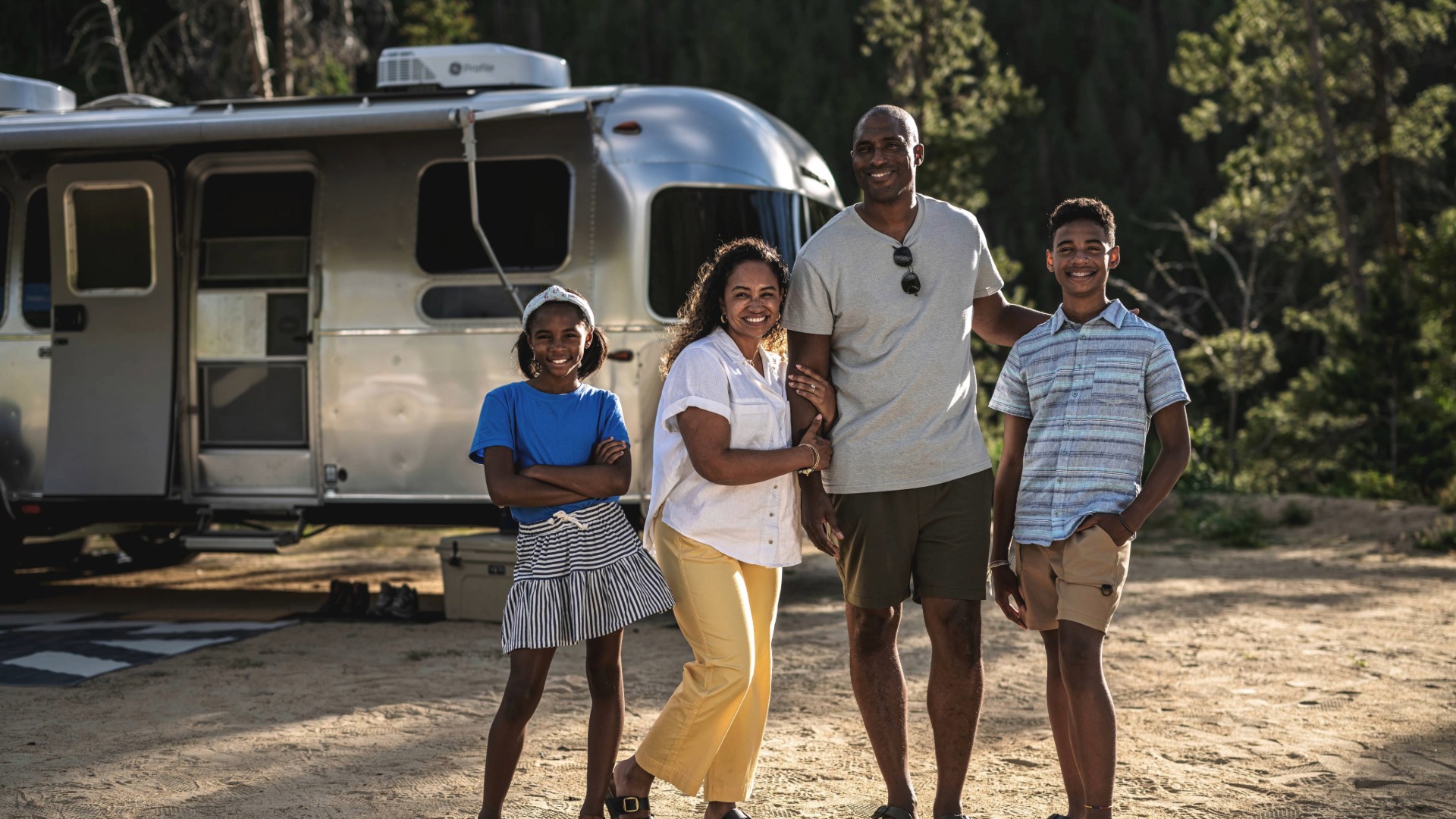 Family of four standing outside the Airstream Flying Cloud Travel Traielr