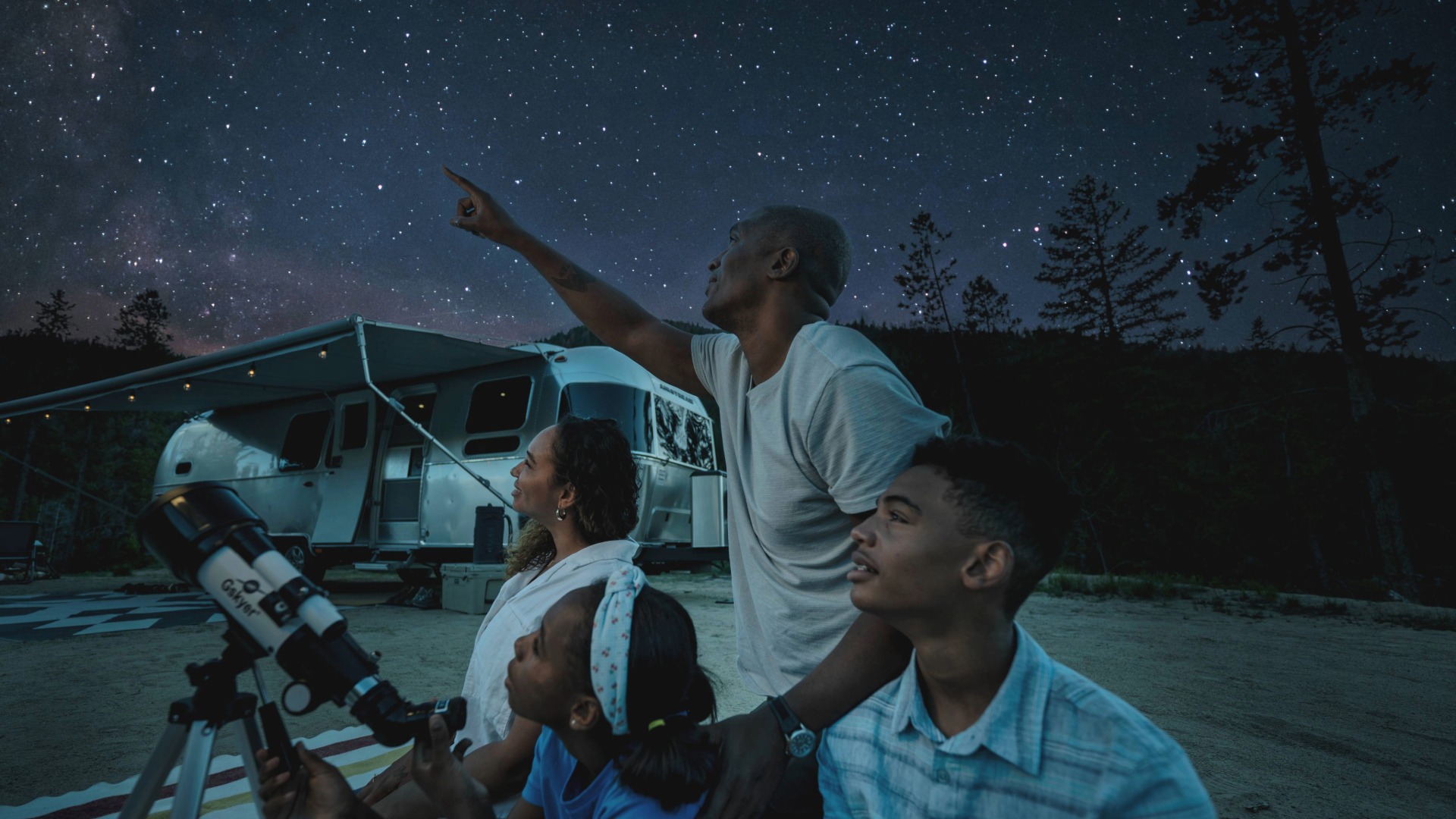 Family stargazing outside in front of an Airstream RV