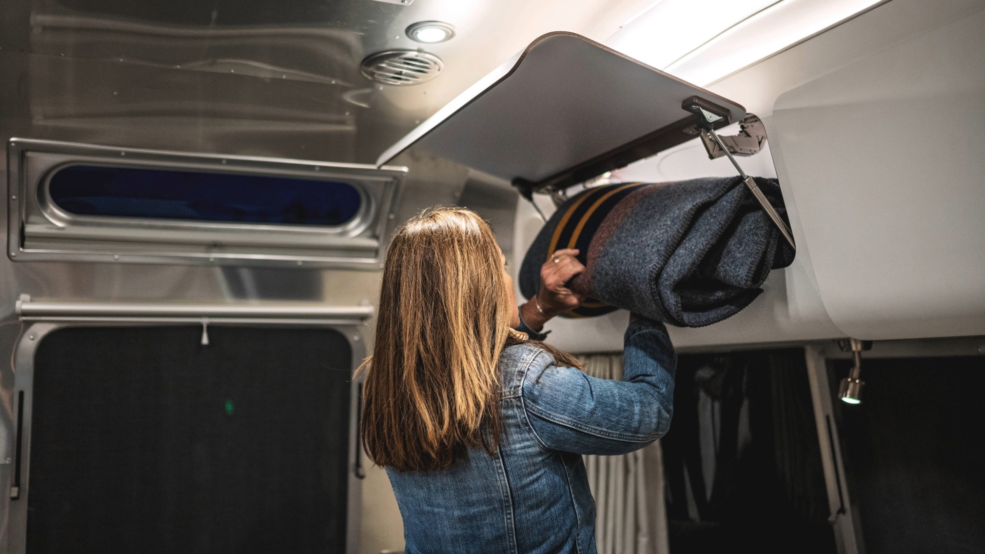 Woman placing blanket in the Globetrotter overhead storage containers
